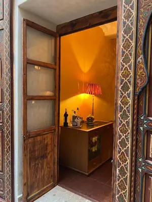 a room with a wooden door and a table with a lamp at Riad Alena in Marrakech