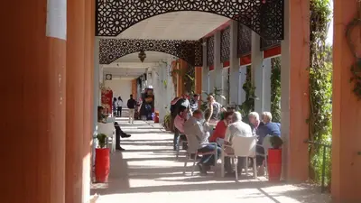 a group of people sitting at tables on a sidewalk at Appartement résidence avec piscine in Marrakech