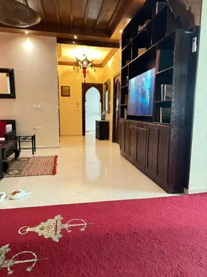 a living room with a television and a red rug at Flair's - Families Only in Marrakech