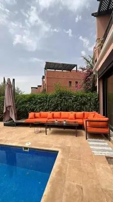 a patio with orange furniture next to a pool at Magnifique villa avec piscine chauffée in Marrakech