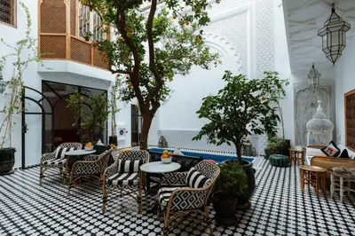 a lobby with chairs and tables and a fireplace at Riad Botanica in Marrakech