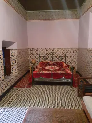 a bedroom with a bed with a red blanket on it at Maison authentique centre médina in Marrakech