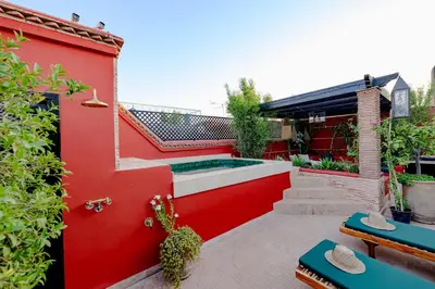 a garden with a red wall and a swimming pool at RIAD DAR C in Marrakech
