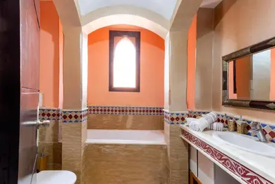 a bathroom with orange walls and a tub and sink at Magnifique villa de 320 m2 avec 2 piscines in Marrakech