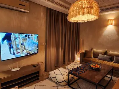 a living room with a couch and a flat screen tv at Riad M. Jacuzzi - Piscine Arty/Cosy - Privatif in Marrakech