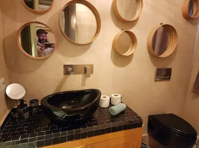 a man taking a picture of a bathroom with a sink and mirrors at Riad M. Jacuzzi - Piscine Arty/Cosy - Privatif in Marrakech