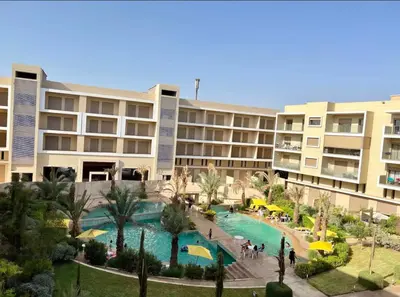 a hotel with a swimming pool in front of a building at pearl garden marrakech in Marrakech