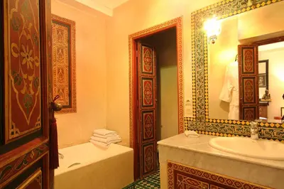 a bathroom with a tub and a sink and a mirror at Riad Esmeralda in Marrakech