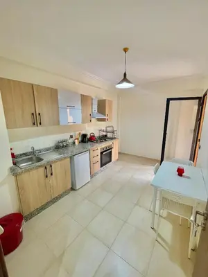 a kitchen with wooden cabinets and a blue table at Cozy Apartment in the City Center - 100% Equipped in Marrakech