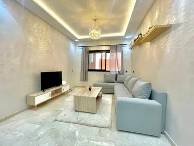 a living room with a blue couch and a tv at Cozy Apartment in the City Center - 100% Equipped in Marrakech