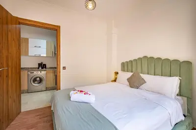 a bedroom with a white bed with a green headboard at Chic & Cosy Appart au Centre Ville - 100 % Équipé in Marrakech