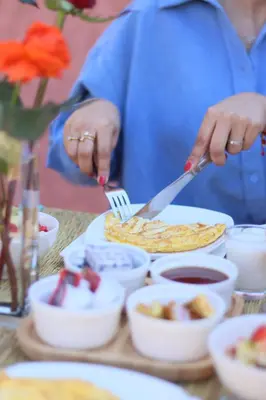 a woman cutting a plate of food with a fork and knife at RIAD MARRAKECH DOORS in Marrakech