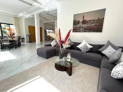 a living room with a couch and a table at Belle et spacieuse villa au Golf Amelkis Marrakech in Marrakech