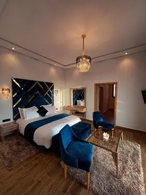 a bedroom with a bed and blue chairs and a table at Villa 7palms in Marrakech