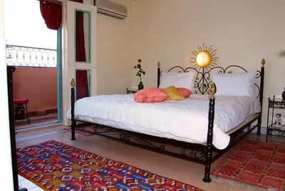 a bedroom with a bed with white sheets and red pillows at Chez Peyo in Marrakech