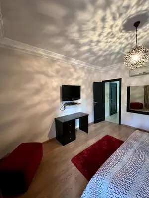 a bedroom with a bed and a flat screen tv at Appartement chambre salon a l'hivernage 9 in Marrakech