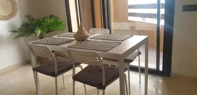 a dining room table with chairs and a table with a plant at Apparemment wafaa in Marrakech