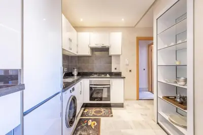 a kitchen with white cabinets and a washer and dryer at NEW! Luxe et moderne en plein Guéliz, Terrasse in Marrakech