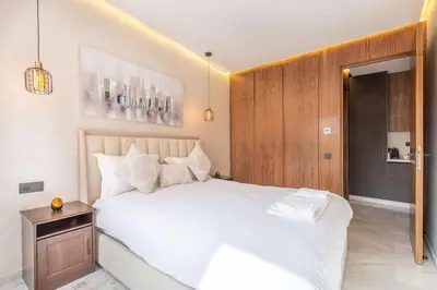a bedroom with a white bed and a wooden cabinet at New ! Stunning and Comfortable apartement in Marrakech