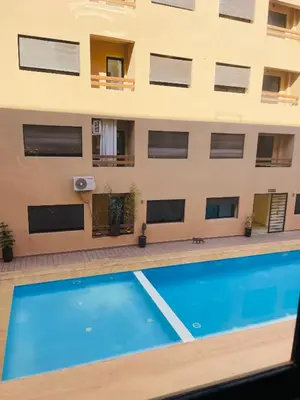 a swimming pool in front of a building at appart à côté de la gare du train in Marrakech