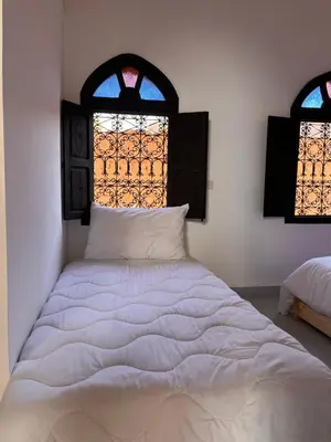 a white bed in a room with two windows at Riad Black Doors in Marrakech