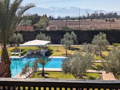 a pool with trees and mountains in the background at Villas Green in Marrakech
