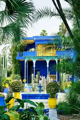 a blue house with palm trees and plants in front of it at Appartement dans résidence avec piscine in Marrakech