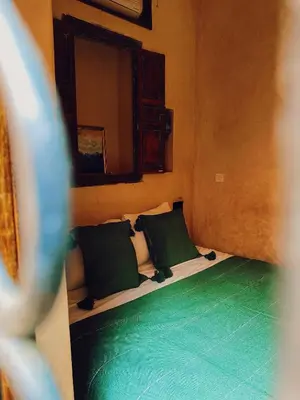a room with a bed with two green pillows at Riad Sidi Radoine in Marrakech
