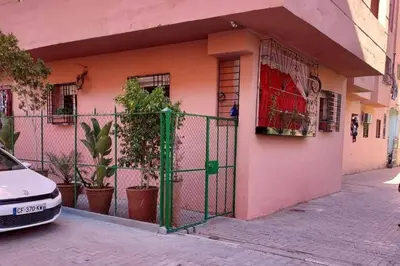 a pink house with a green gate in front of it at proche aéroport, idéal pour travailler in Marrakech