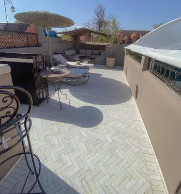 a patio with tables and chairs and an umbrella at Riad Dar Marrakcha in Marrakech
