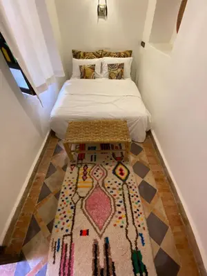 a small bedroom with a bed and a rug on the floor at Riad Musa in Marrakech