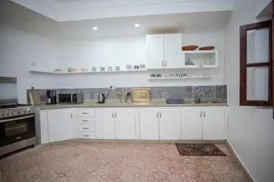 a white kitchen with white cabinets and a sink at Paisible riad privatif au cœur de Marrakech in Marrakech