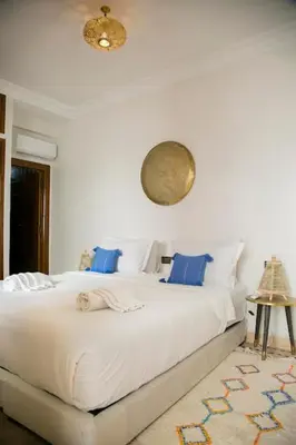 a bedroom with a large white bed with blue pillows at Riad Sabria in Marrakech