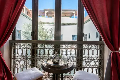 a balcony with a table and a large window at Riad le Jardin de Mina in Marrakech