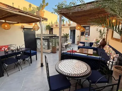 an outdoor patio with a table and chairs and an umbrella at Magnifique Riad Julilu Privatise au coeur de la Medina 11P in Marrakech