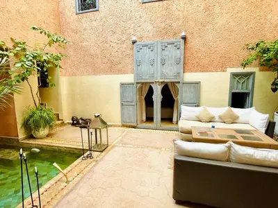 a patio with a couch and a pond in front of a building at Exclusive and stylish 4-bedroom Riad with plunge pool in Marrakech
