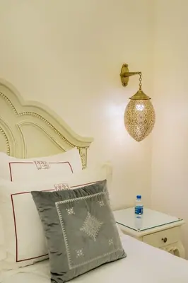 a bedroom with a bed with a lamp and a table at HOTEL RIAD CHAMI in Marrakech