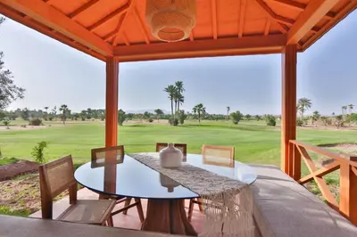 a patio with a table and chairs and a golf course at Villa May sur le Golf de la Palmeraie with Cooker and Butler included in Marrakech