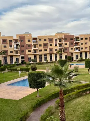 a large apartment complex with a palm tree and a building at Appartement en résidence privée in Marrakech