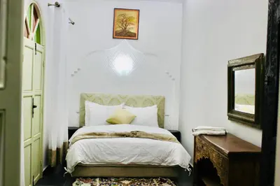 a bedroom with a bed and a mirror and a window at DAR Riad Jomana in Marrakech