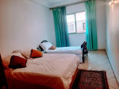 a bedroom with two beds and a window with green curtains at Espace Harmony in Marrakech