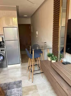 a kitchen with a table and chairs in a room at Duplex Cosy dans résidence avec piscine in Marrakech