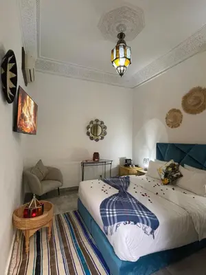 a bedroom with a bed and a table and a lamp at RIAD KECHMARA in Marrakech