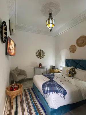 a bedroom with a bed and a table and a chair at RIAD KECHMARA in Marrakech