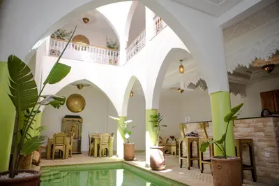 a room with a pool and tables and plants at Riad Petite Rose in Marrakech