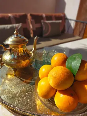 a bowl of oranges on a glass table with a teapot at Riad Doum Collection 1 in Marrakech