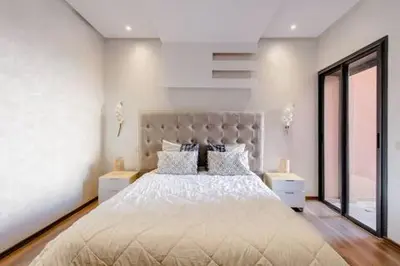 a white bedroom with a large bed with white sheets and pillows at Appartement résidence Marrakech haut standing piscine in Marrakech