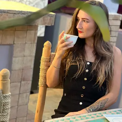 a woman sitting at a table drinking a cup of coffee at Riad Pourpre Medina in Marrakech