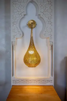 a gold light fixture in a white wall at Riad Glatt K in Marrakech