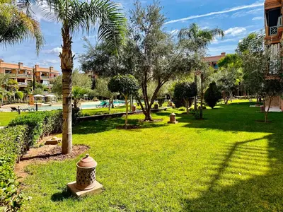 a park with a palm tree and a fire hydrant at Chic Moroccan Vibes & Pool View - 2BR in Marrakech